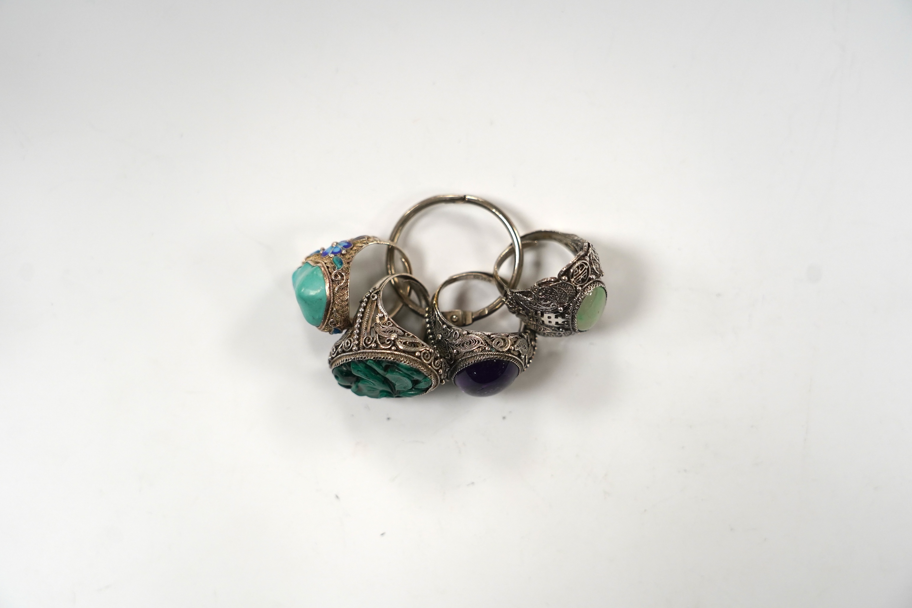 Four assorted Chinese white metal filigree and gem set rings, including turquoise and amethyst.